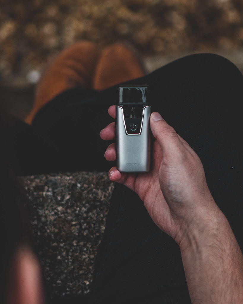 Hand holding a small silver pod vape device